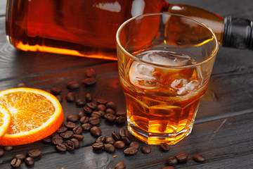 Whiskey or liqueur, coffee beans and orange cut on wooden background. Seasonal holidays concept.