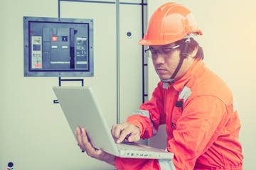 engineer or electrician holding laptop for inspect and checking main distribution board by wifi...