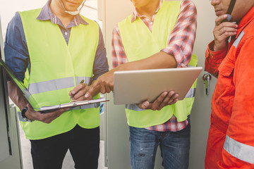 engineer or electrician holding laptop for inspect and checking main distribution board by wifi...