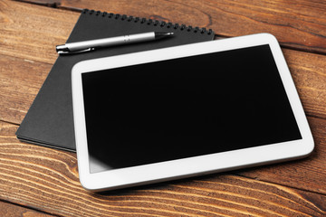 Tablet with notepad on wooden background