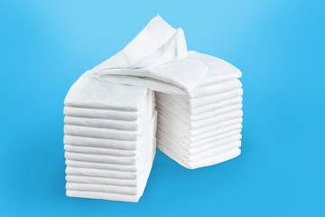 Stacks of adult disposable diapers on a blue background. Health care for elderly and bedridden...