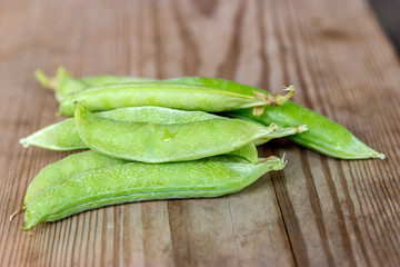 green fresh pea pods on a wooden background