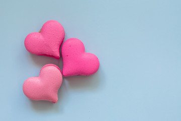 Fototapeta premium heart-shaped macaroons on blue background.Valentine's Day. Pink gift tied with rosy ribbon and macaron macaroon cookie on pink heart background top view. Valentines Day, 8 March, Womens Day, Birthday