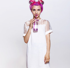 Beautiful girl  in white dress with glitter make-up and pink hair  holding a glass of water in her hands on white background