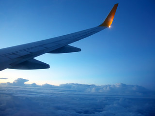 Obraz premium The wing of an airplane above the clouds