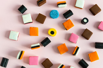 Heap of colorful Liquorice allsorts on pink background. Sweets