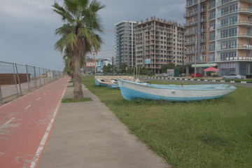 Fototapeta premium Seaside promenade in Batumi. Boat on the shore. View of Streets Beach Batumi Boulevard
