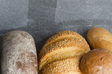 Freshly baked different kinds of bread on grey table