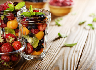 Assorted berries in mason jar on kitchen wooden table