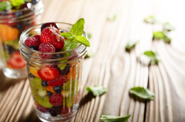 Assorted berries in mason jar on kitchen wooden table