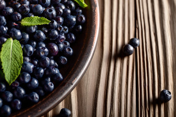 Clay plate full of Ripe organic blueberries on wooden table