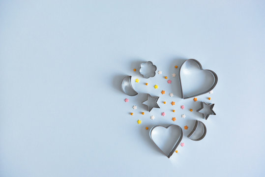 Metallic cookie cutters in heart shape on blue background. Bakery and confectioner concept. Copy space