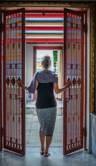 Woman opens an iron gate walks into the temple