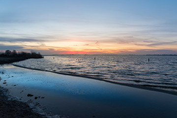 Sunrise on the horizon above a lake with beach in the Green Heart of the Netherlands, Europe. Reeuwijkse Hout.