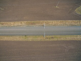 aerial view of railroad tracks in the backcountry between freshly plowed farmland - top view of the train tracks