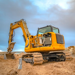 Excavator on top of dirt with cloudy sky overhead