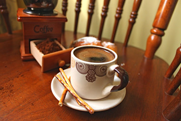 Coffee cup and coffee grinder in the background.
