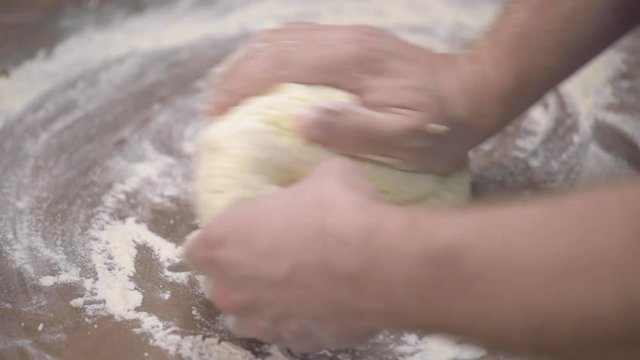 Baker Kneading Dough in Flour on the Kitchen Table. Man Chef Making Cookies at Home. Close up view of Man Hands Preparing Dough for Curd Pancakes.