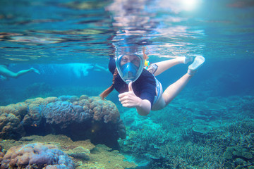 Young woman snorkeling undersea. Snorkel show thumb up under water. Woman in full-face snorkeling mask