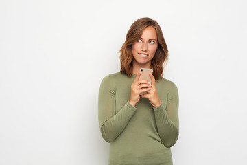portrait of young woman with phone biding lip 