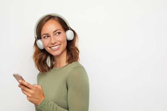 portrait of a young smiling woman with headphones and mobile phone 