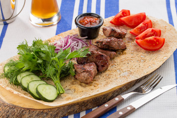 Fresh, homecooked on the grill fire meat beef shish kebab with vegetables with barbecue sauce on textile background