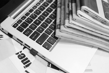 Newspapers and laptop. Pile of daily papers with news on the computer. Pages with headlines,...