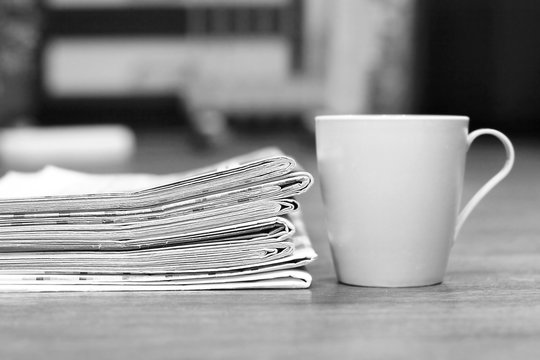 Stack of newspapers and cup of tea. Daily papers stacked in pile and morning coffee, concept for reading paper media during breakfast 