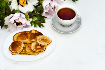 Obraz na płótnie Canvas tea and pancakes on the background of beautiful pions.