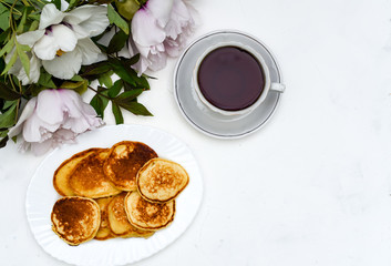 Obraz na płótnie Canvas tea and pancakes on the background of beautiful pions.