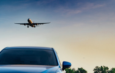 Commercial airline. Passenger plane landing approach blue SUV car at airport with blue sky and...