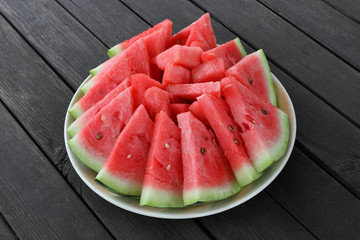 Plate with sliced watermelon on a wooden table.