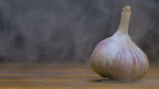 garlic bulb is on the table in cold, steam from frost in slow motion, cloese up