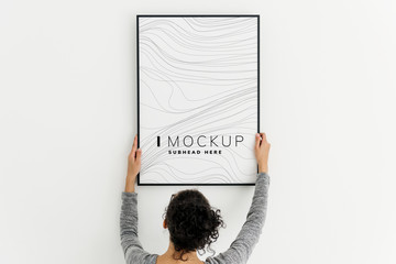 Woman putting up an art piece mockup at home