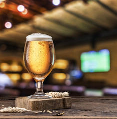 Chilled glass of light beer on old wooden table.