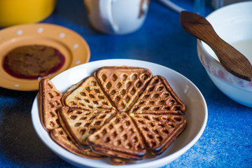 Macro shot of just cooked, delicious, tasty and hot yogurt pancakes with strawberry sauce on yellow and white plates in kitchen, next to stove. Dinner is ready. Sweet golden brown waffles with jam