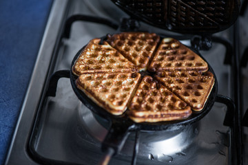 Just cooked, delicious, tasty, hot yogurt pancakes on waffle iron on fire stove in kitchen. Dinner is ready. Sweet golden brown waffles ready to be eaten