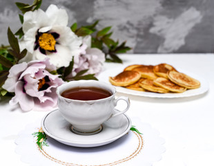 tea and pancakes on the background of beautiful pions.