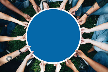 Group of people holding a round blue board