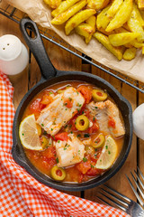 Cod fish cooked in tomato sauce with olives, lemon and tomato