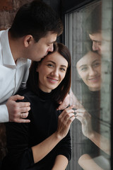 Obraz premium Happy couple of lovers sit on the windowsill. Christmas atmosphere at home. Young family together