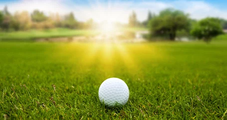 Deurstickers Golf ball on green grass on blurred beautiful landscape of golf course with sunrise,sunset time on background.  © Nischaporn