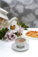 tea and pancakes on the background of beautiful pions.