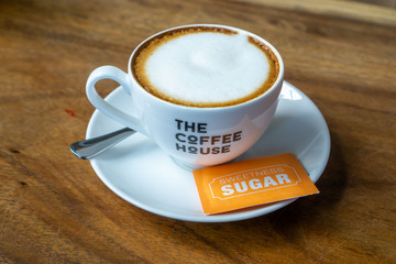 Top View of a Cappuccino with Table Spoon and Sugar on a Wooden Table