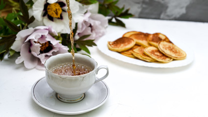 tea and pancakes on the background of beautiful pions.