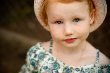 european girl with red hair and green eyes in a summer hat