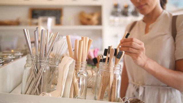 Young Mixed Race Woman Choosing Bamboo Eco Friendly Biodegradable Toothbrush in Zero Waste Shop. No plastic Conscious Minimalism Vegan Lifestyle. Reduce Reuse Recycle 4K Slowmotion Concept.