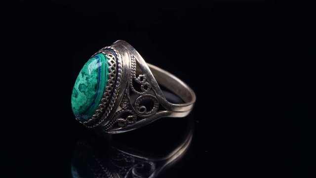 Old melchior ring with malachite stone on a black background. Close up.