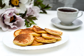 tea and pancakes on the background of beautiful pions.