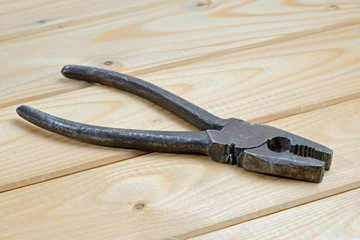 Old rusty pliers on wooden background. Close up